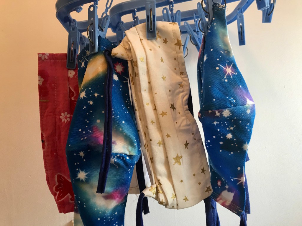Homemade masks hanging from a laundry rack.